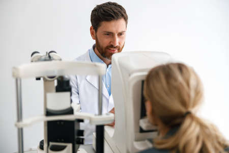Male ophthalmologist checks a patients vision at an opticians shop or ophthalmology clinic