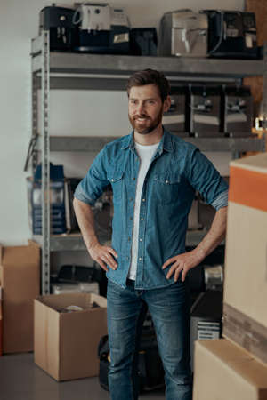 Repairman standing on warehouse with coffee machines on backgroundの写真素材