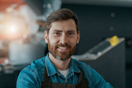 Portrait of smiling business owner on the background of coffee small factory