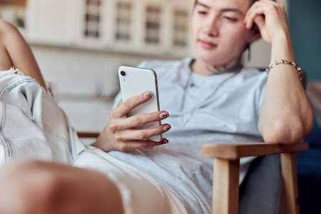 Asian guy sitting at his flat while using mobile phoneの写真素材