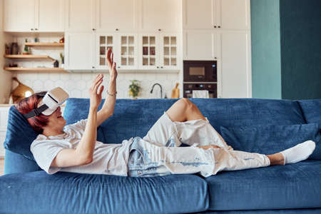 Happy Asian guy using VR headset and playing video games at his flatの写真素材