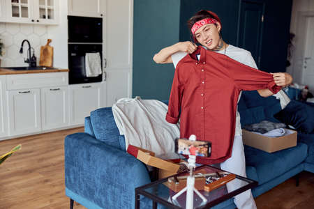 Happy Asian guy during online broadcast making sale of things at homeの写真素材