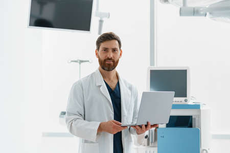 Professional doctor standing with laptop in operation room of modern clinicの写真素材