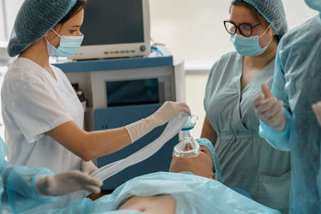Well-trained anesthesiologist follows the patient during the surgery in clinicの写真素材