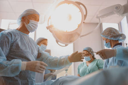 Operating nurse gives clamp to surgeon, the styryl space is needed by patient during an operationの写真素材