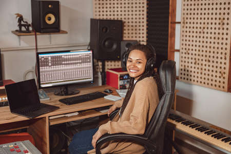 Beautiful stylish African woman audio engineer, musician and producer working in music recording studio soundproof roomの写真素材