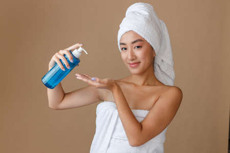Smiling Asian woman using moisturizing lotion after shower