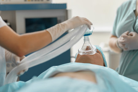 Close up hands of doctor anesthesiologist holding breathing mask on patient face during operation