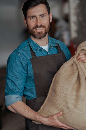 Portrait of baristas in uniform standing with bag full of coffee beans at coffee storeの写真素材