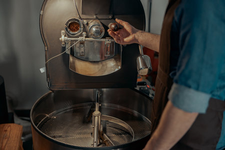 Close up of business owner hands operating modern coffee bean roasting machineの写真素材