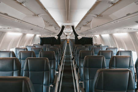 Commercial aircraft cabin with rows of seats down the aisleの写真素材