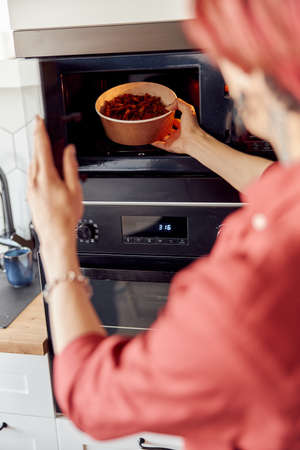 Male hands giving foods into the microwave for warm upの写真素材