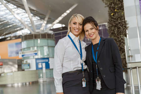 Portrait of smiling female airport employees at their workplace in terminal looking cameraの写真素材