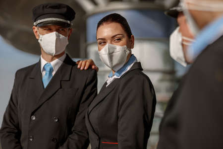 Pilot and stewardess in masks looking at their colleagues