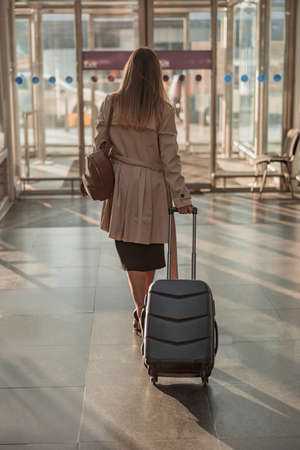 Lady with suitcase and backpack at the airport going to the exitの写真素材