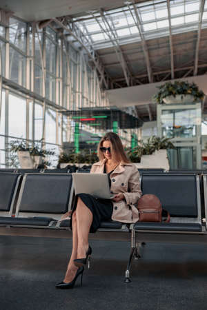 Young woman using laptop sitting in waiting hall at the airportの写真素材