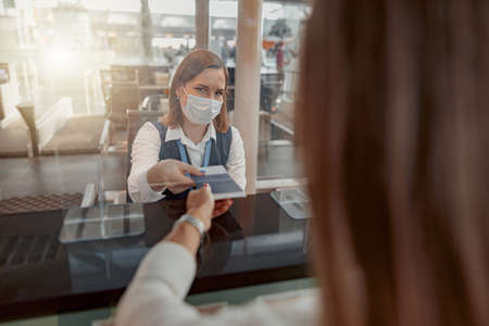 Female employee in mask checking passports and biometric dataの写真素材