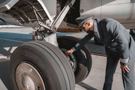 Pilot in uniform checks the aircraft before the flight in airport