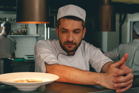 Tired chef on kitchen restaurant waiting for a new order and looking on ready dishの写真素材