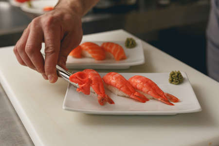 Close up of sushi master prepares sushi for serving in modern commercial kitchenの写真素材