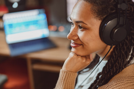 Close-up charming African woman, songwriter, sound engineer, singer with headphones working on music recording studioの写真素材