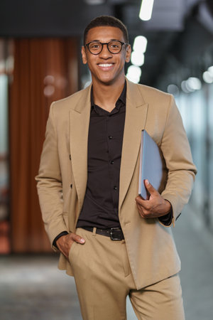 Handsome smiling african businessman with documents standing in modern coworkingの写真素材