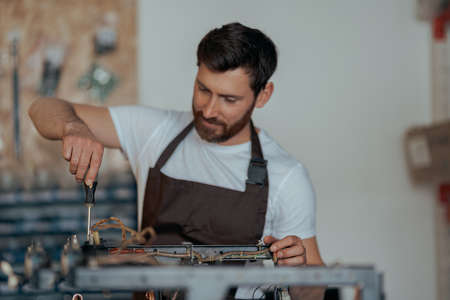 Smiling young worker repairing coffee machine in a workshopの写真素材