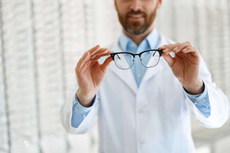 Male optician on a background of shop windows with different models of glassesの写真素材
