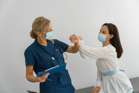 Doctor wearing protective mask  elbowing touching in greeting with patientの写真素材