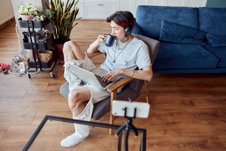 Young Asian man using laptop and listening to music with headphonesの写真素材