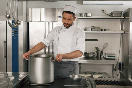 Chef cooking tasty dish in kitchen of restaurant using modern equipmentの写真素材
