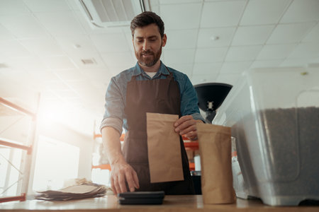 Uniformed worker packs roasted coffee beans into packages for sale