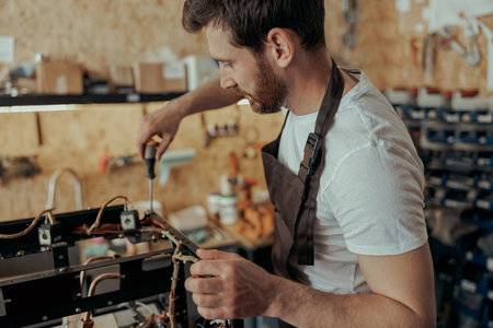 Smiling young man repairing coffee machine in a workshopの写真素材