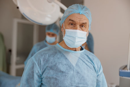 Portrait of senior surgeon standing in operating room, ready to work on patientの写真素材