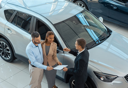 Happy beautiful couple is choosing a new car at dealershipの写真素材
