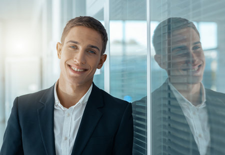 Young male businessman standing in auto show office and looking at camera. Blurred backgroundの写真素材