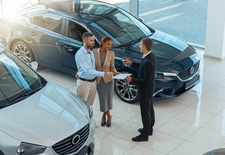 Happy beautiful couple is choosing a new car at dealership. Blurred backgroundの写真素材