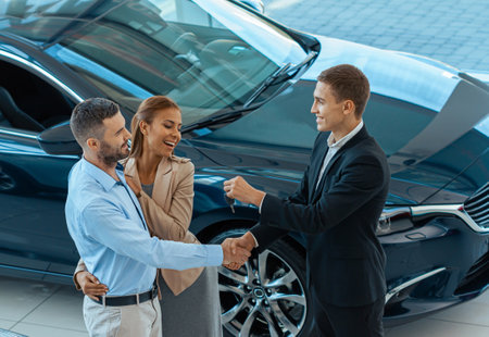 Happy beautiful couple is choosing rental car at dealership for travelingの写真素材