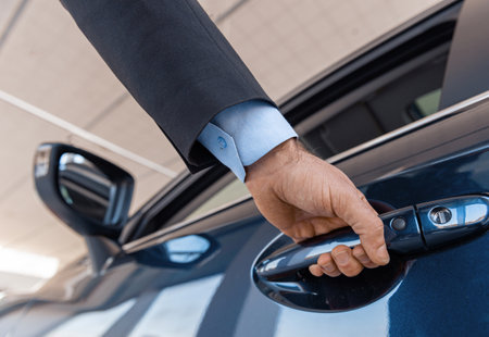 Close up of a male businessman hand opening a car door at the dealershipの写真素材