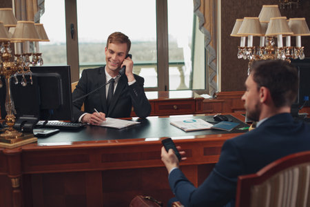 Receptionist and customer on reception desk talking phone in luxury hotelの写真素材
