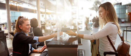Female traveler giving her passport to an airport staff memberの写真素材