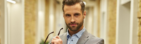 Handsome young businessman holding his spectacles indoorsの写真素材