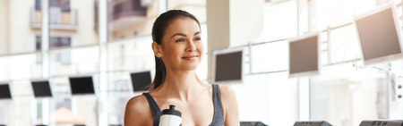 It was a great cardio workout Young and beautiful woman in sportswear holding a bottle with water and resting after running on a treadmill at gym.の写真素材