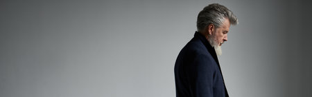 Serious stylish middle aged man in business casual wear looking pensive while standing against white backgroundの写真素材