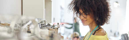 African-American lady designer with glasses and tape measure near rack with basic patternsの写真素材