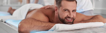 Happy mature man undergoes massage procedure with professional chiropractics in clinicの写真素材