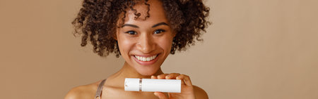 Young woman holding bottle with beauty product in studioの写真素材