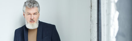 Stylish middle aged man in business casual wear looking at camera, adjusting his suit while posing...