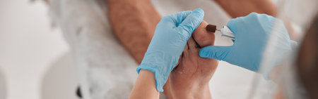 Pedicure master removes dry skin from toe of man with grinding tool in salonの写真素材