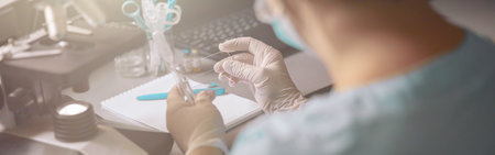Woman covers transparent liquid drop with slide to research at table in labの写真素材